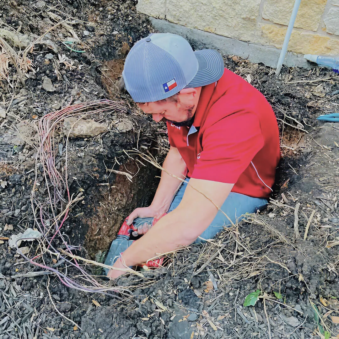 Plumber in hole fixing underground pipes.