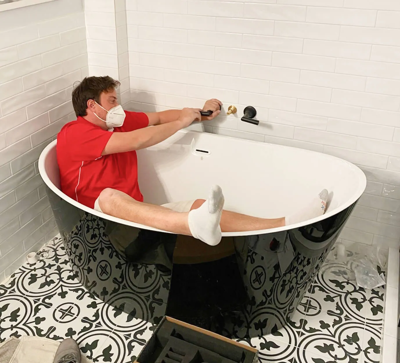 Plumber in bathtub fixing faucet