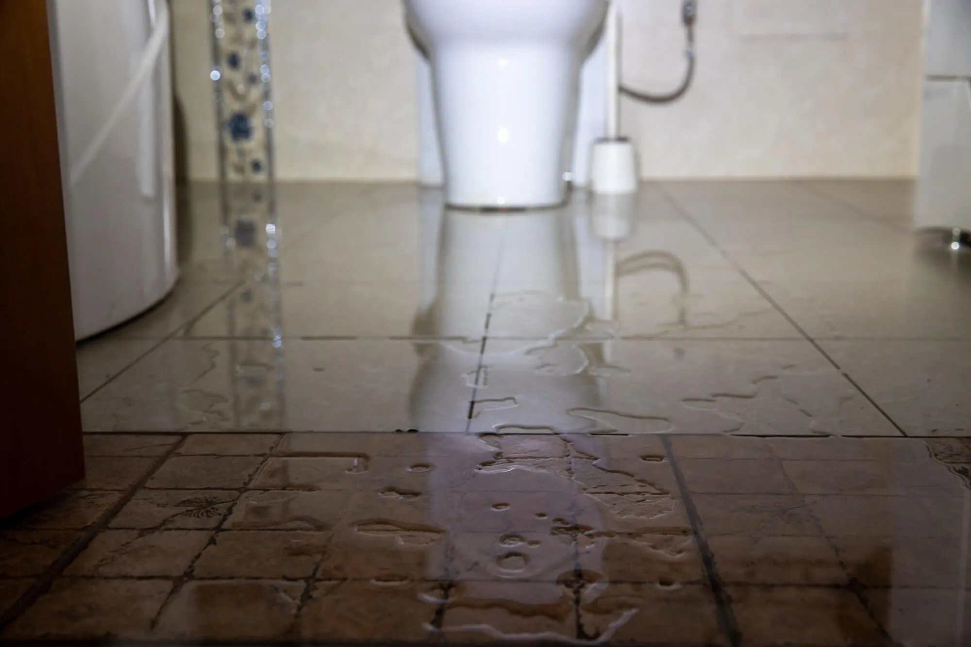 Bathroom floor with toilet leaking water from the bottom.