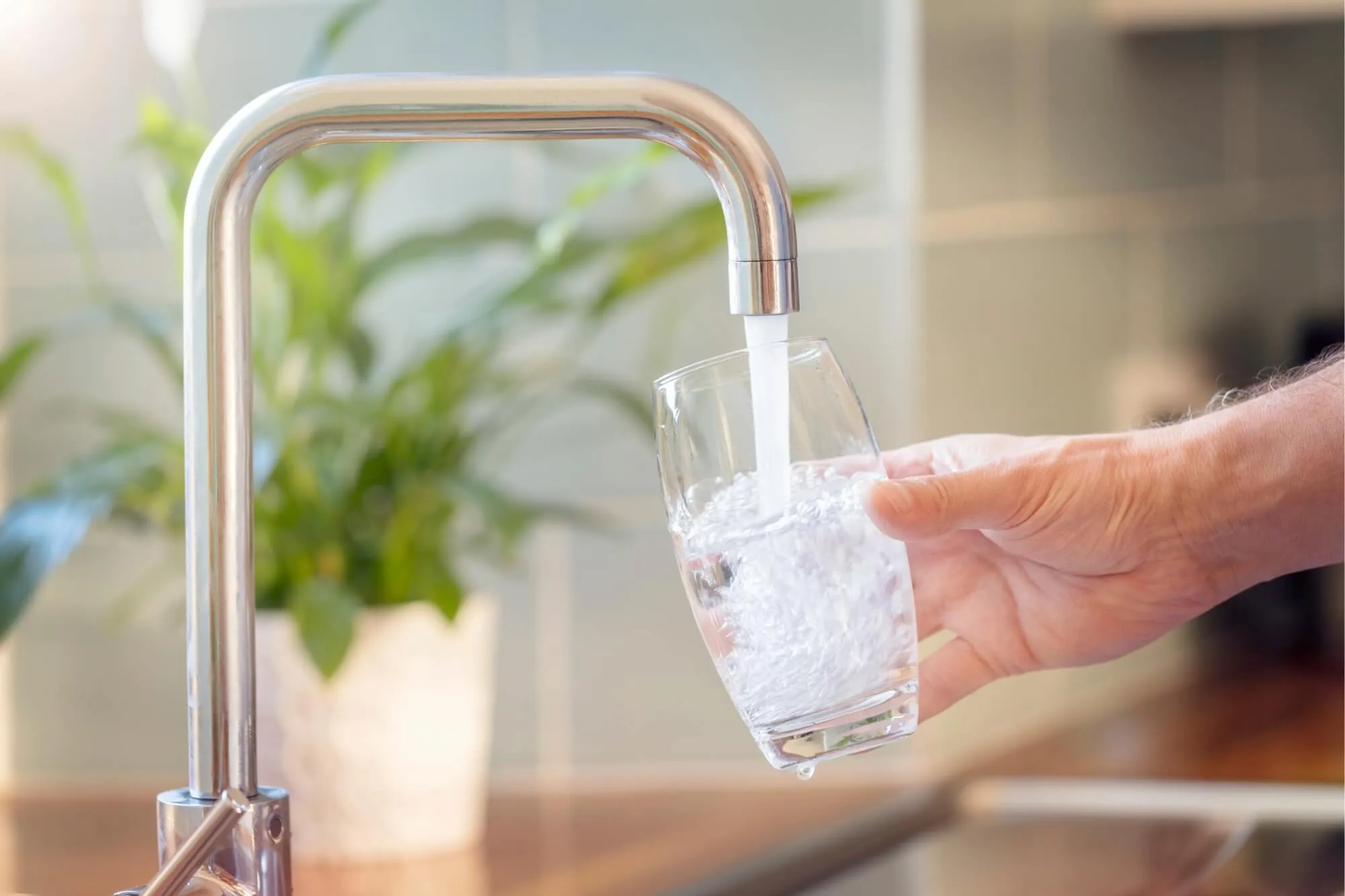 Hand filling glass with tap water.
