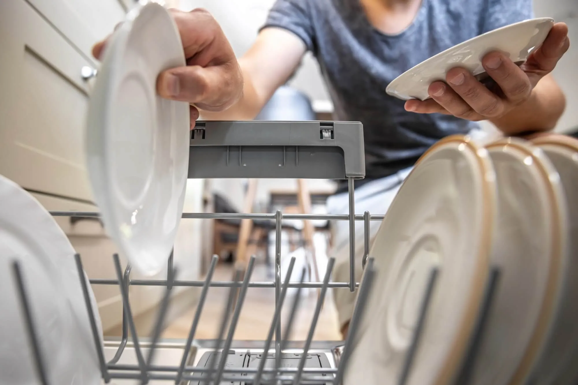 Person loading dishwasher with plates.