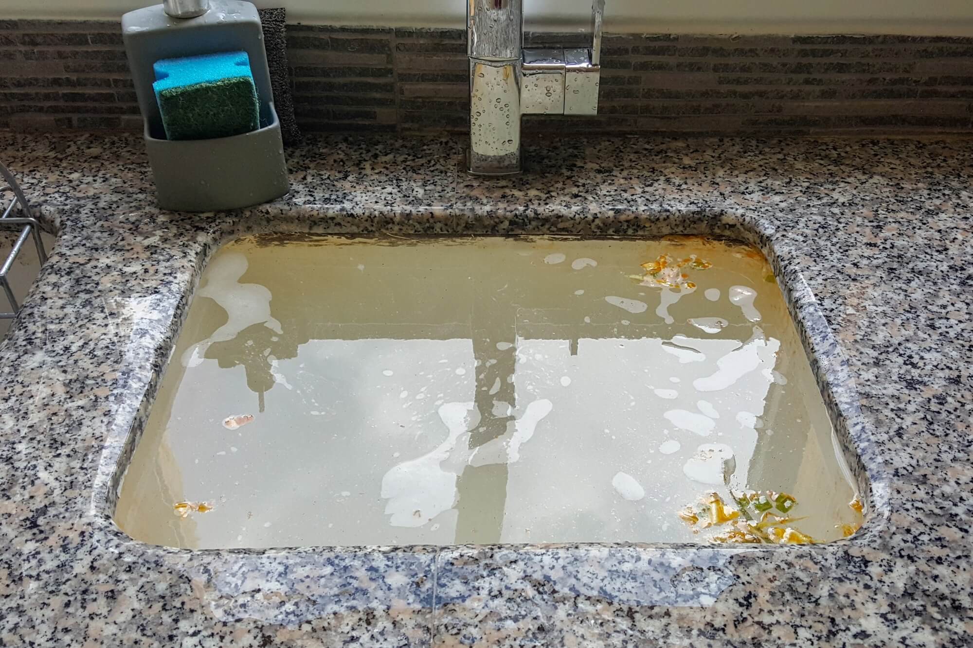Clogged kitchen sink with dirty water.