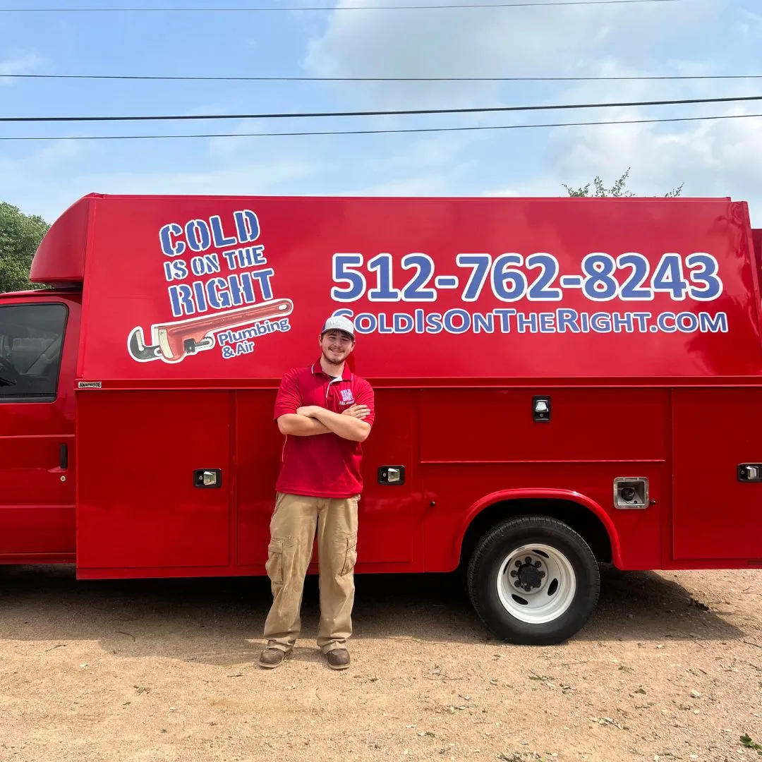 Man in red shirt and cap standing with arms crossed in front of a red service truck with 'Cold is on the Right Plumbing & Air' logo
