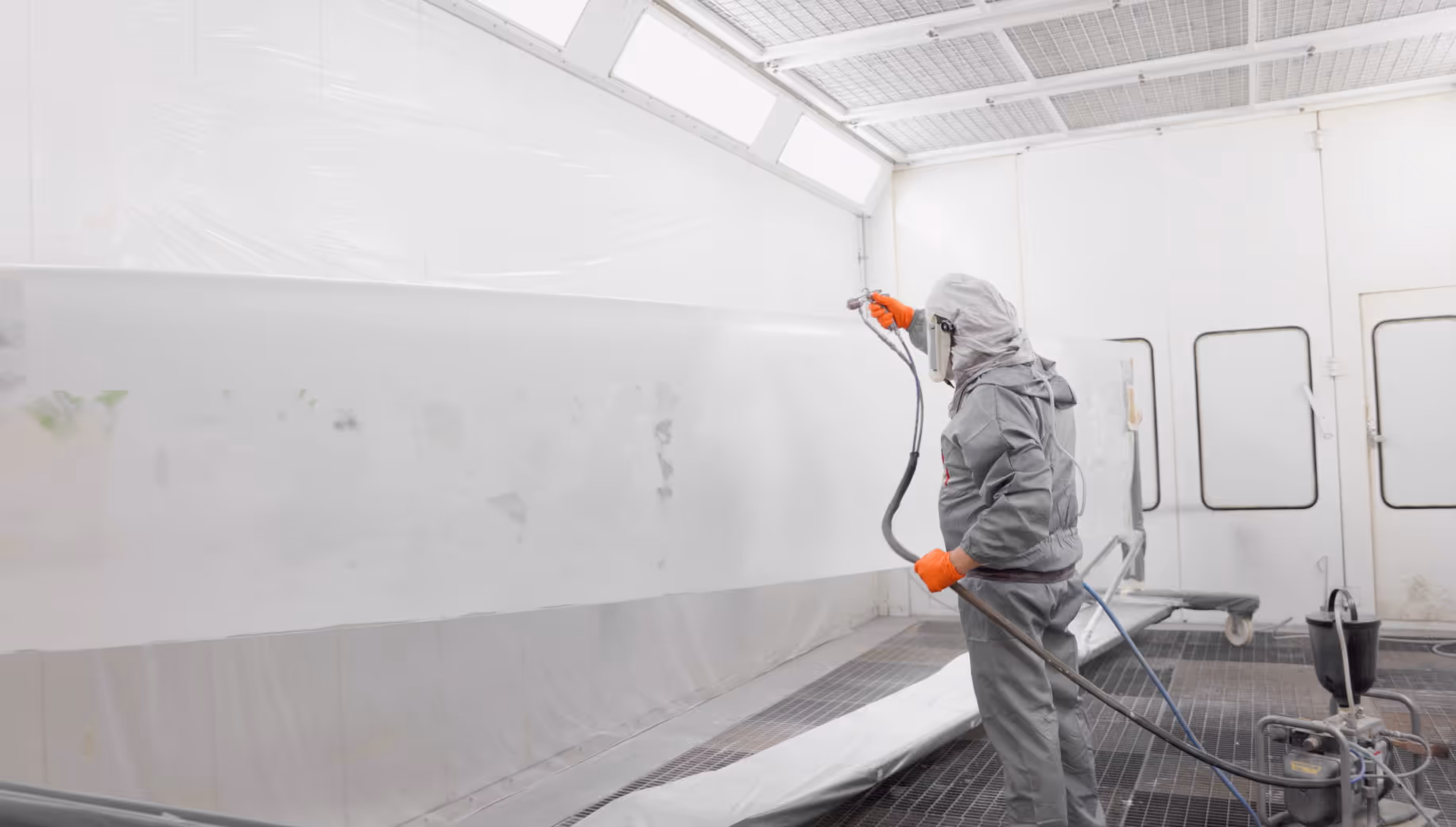 Bergolin employee in protective suit spraying a large area in a coating room.