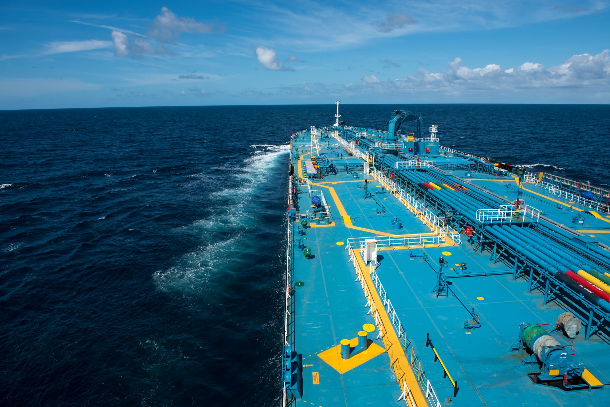 Blau beschichtetes Deck eines Tankschiffs mit gelben Laufwegen auf hoher See.