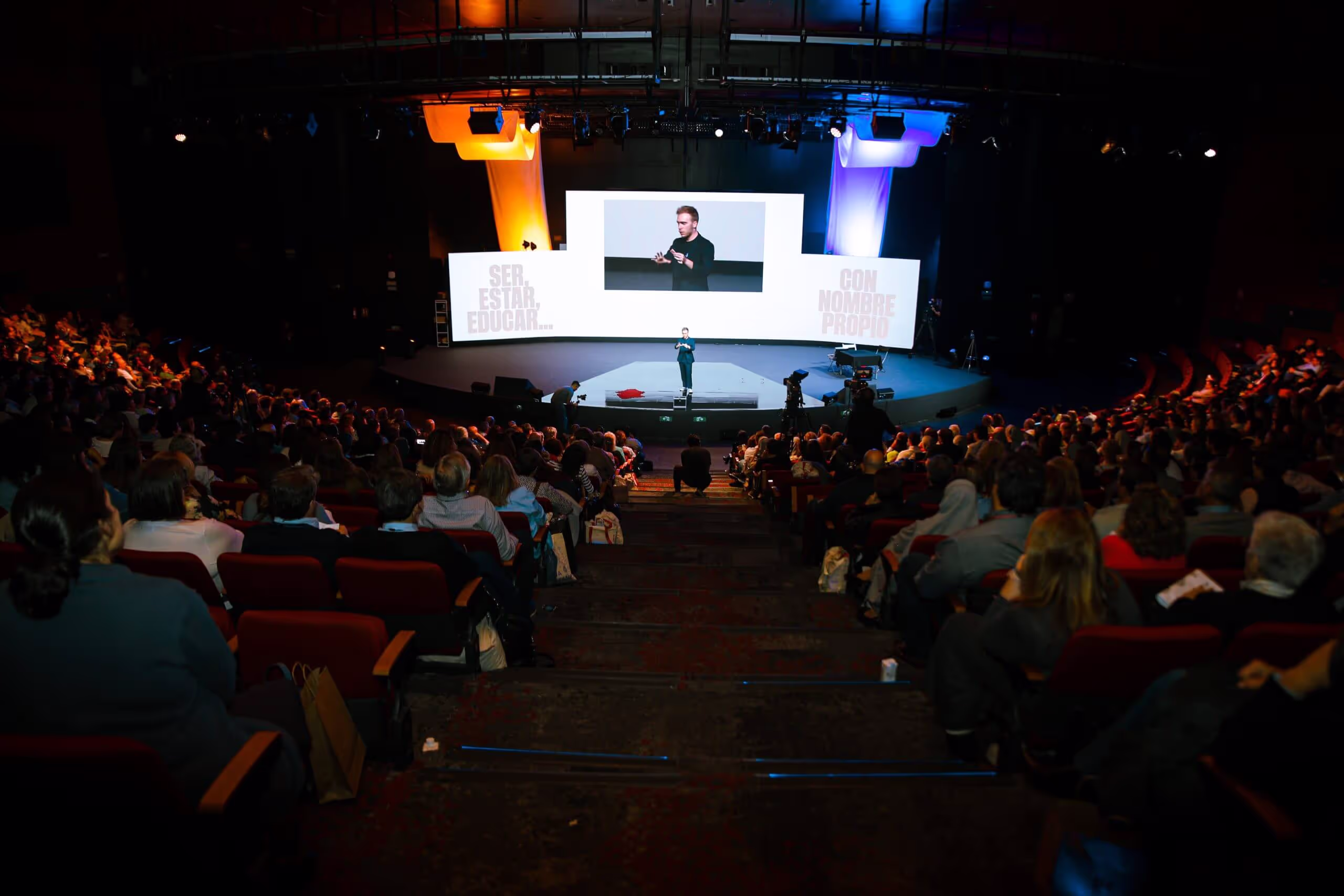 Mago en escenario haciendo magia para los empleados de una empresa en un auditorio.