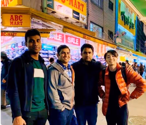 Our founders standing on a busy street at night with bright store signs in the background.