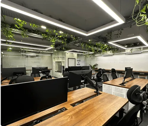 2021年12月に設立された、木製デスクとグリーン装飾が特徴のモダンなワークスペースのJIITAKインドオフィスの内観。