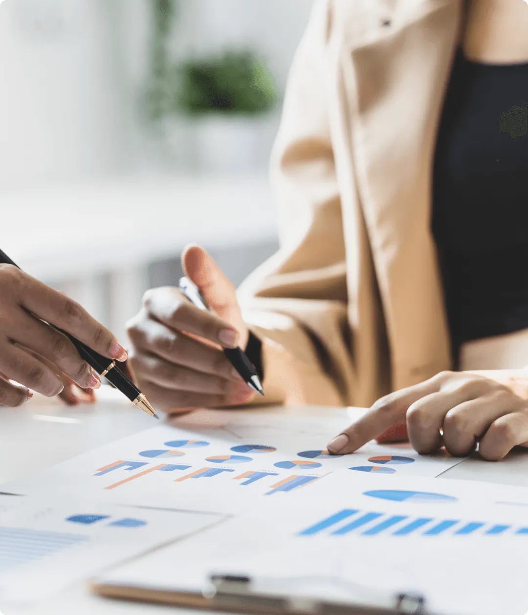 印刷されたチャートやグラフを分析し、ペンでグラフを指しながら実現可能性について議論する2人。