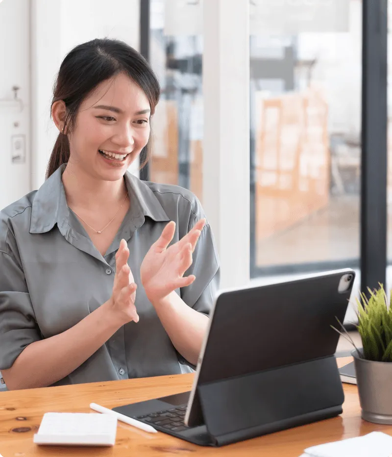 ノートパソコンに向かってジェスチャーしながら微笑む女性。アイデアのヒアリングとユーザー体験モデリングプロセスを象徴。
