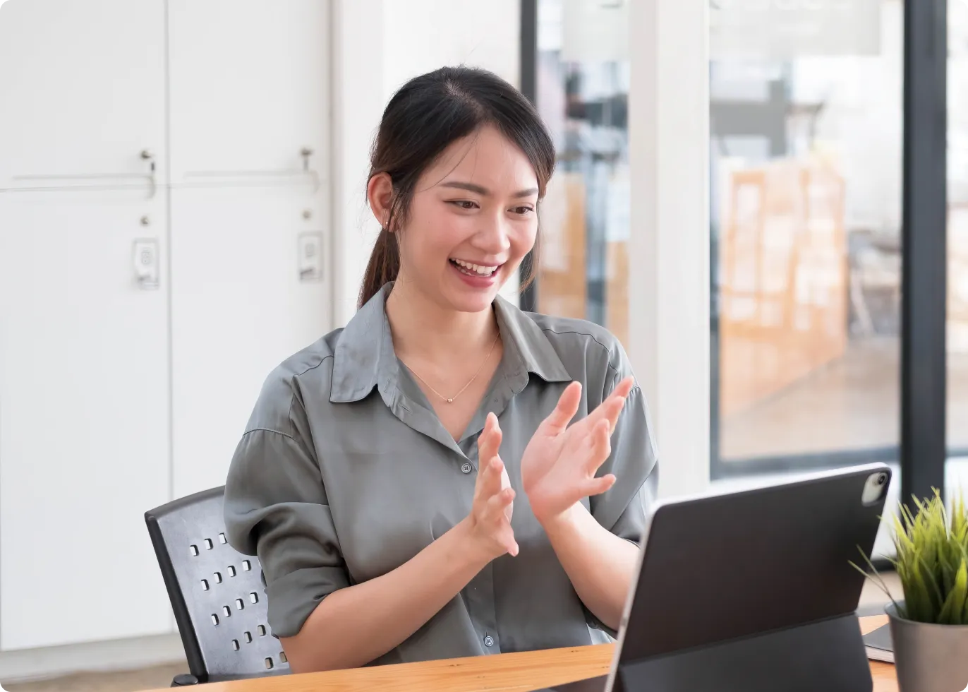 ノートパソコンに向かってジェスチャーしながら微笑む女性。アイデアのヒアリングとユーザー体験モデリングプロセスを象徴。