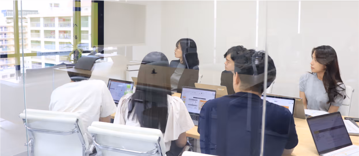 多様な文化的背景を持つJIITAKのチームメンバーが協力し、笑顔で交流している様子。チームワークとイノベーションを象徴。