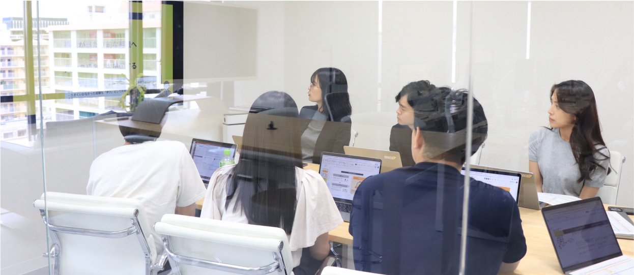 多様な文化的背景を持つJIITAKのチームメンバーが協力し、笑顔で交流している様子。チームワークとイノベーションを象徴。