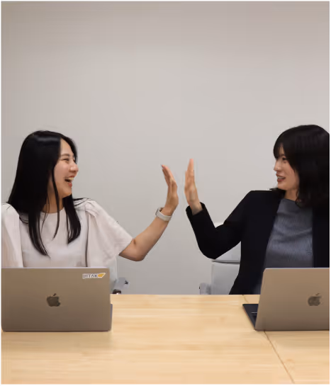 JIITAKのチームメンバーがノートパソコンを囲んでアイデアを共有し、協力している様子。共に成長するというコンセプトを表現。