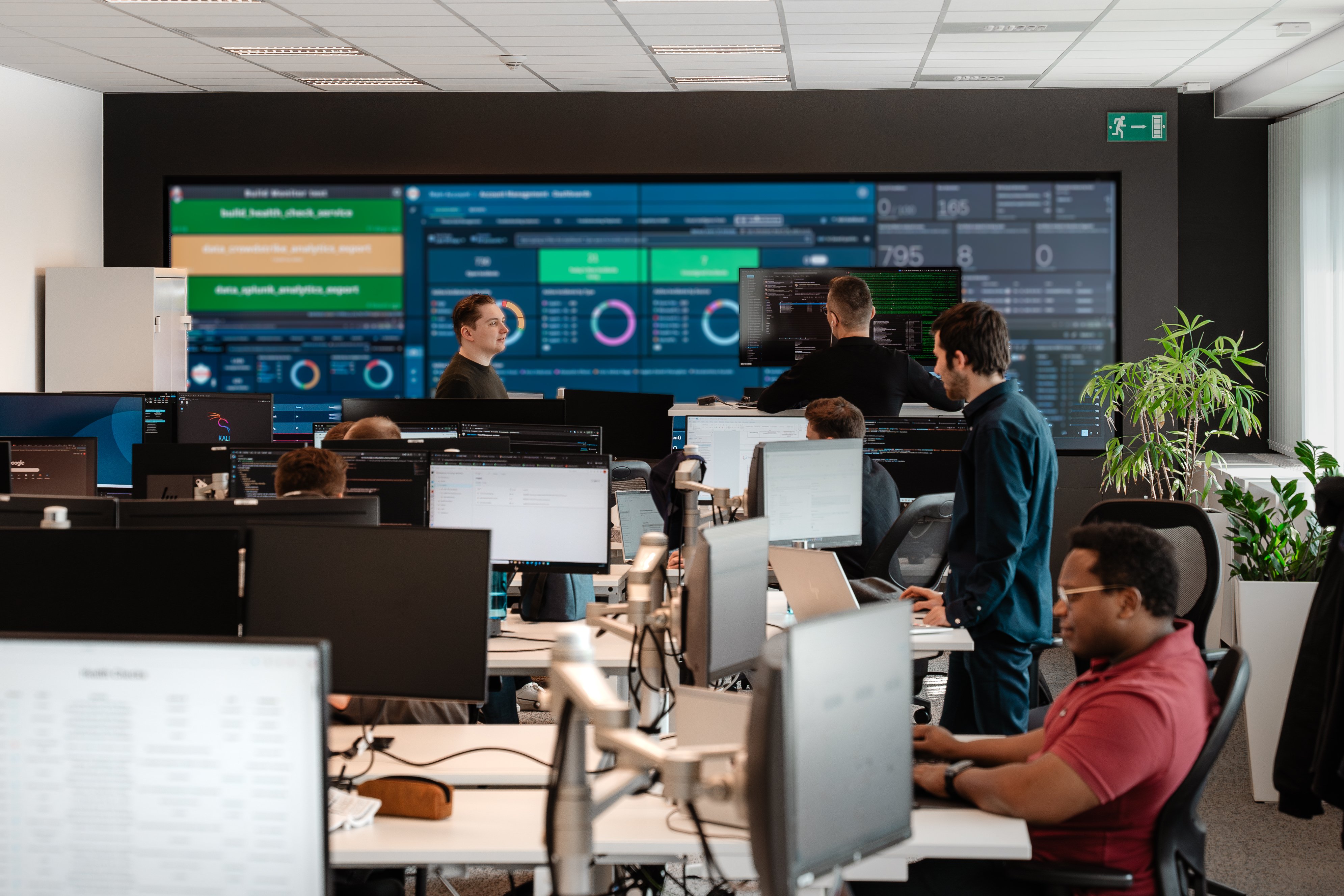 Cegeka team working in a technology operations office with monitoring dashboards.