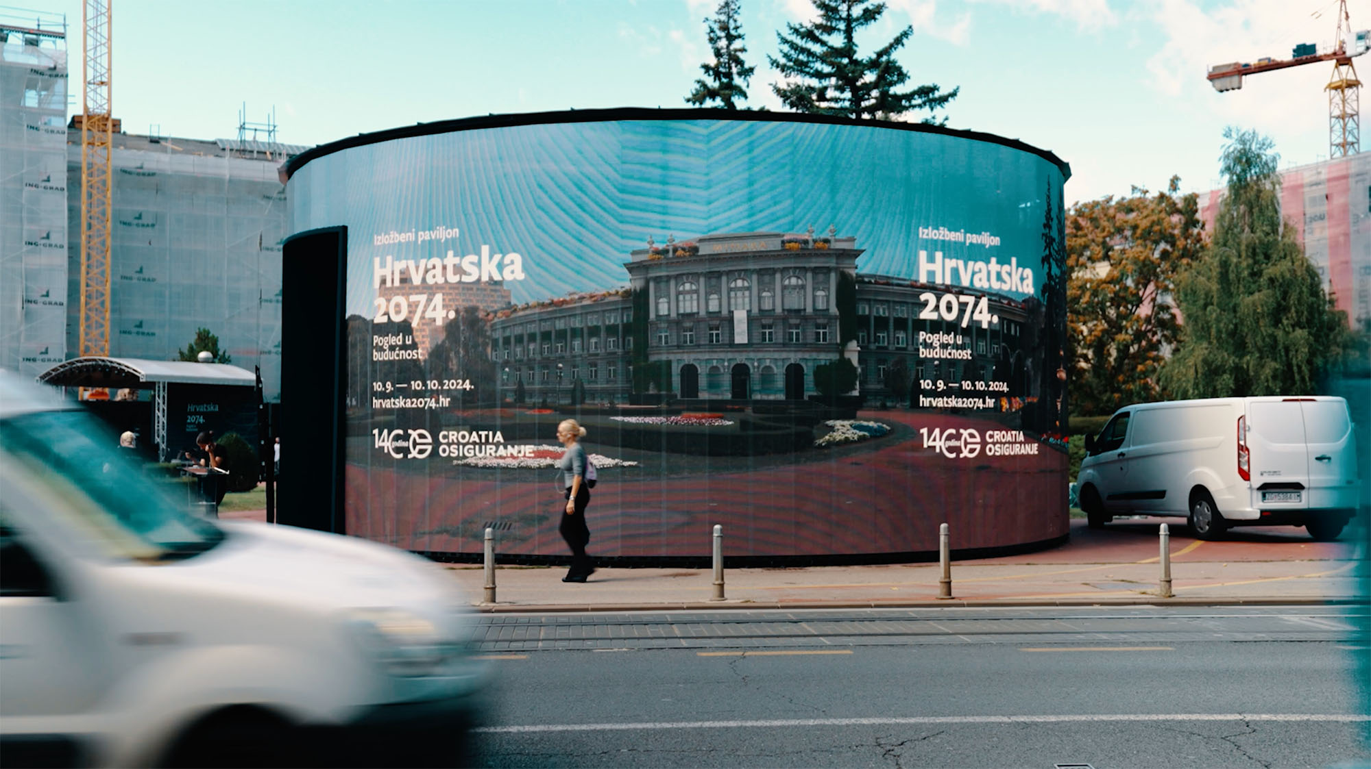 Hrvatska 2074: zakrivljeni LED paviljon s vizualima Croatia osiguranja iz ulične perspektive, pješak prolazi pokraj