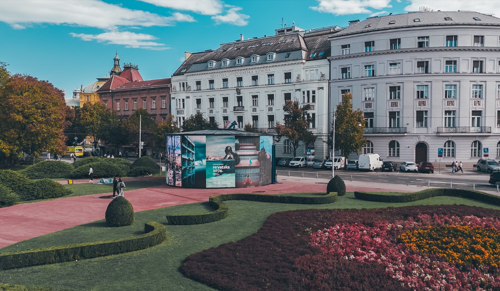 Hrvatska 2074: brendirani okrugli paviljon na uređenom trgu s cvjetnim gredicama i povijesnim zagrebačkim pročeljima