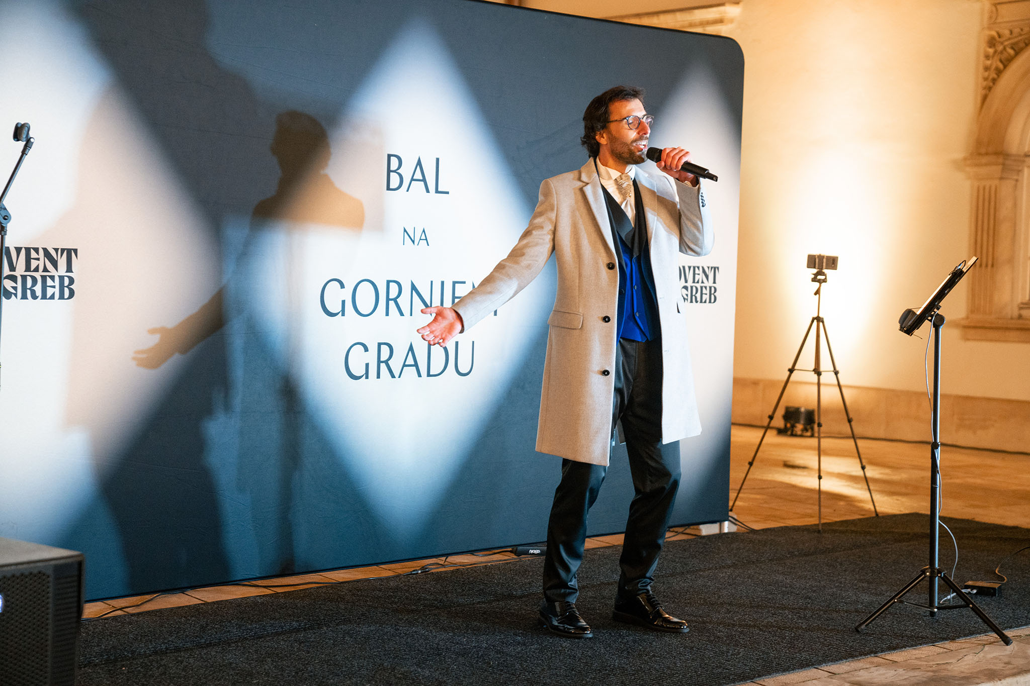 Voditelj s mikrofonom na pozornici ispred pozadine s natpisom Bal na Gornjem gradu i logom Adventa Zagreb
