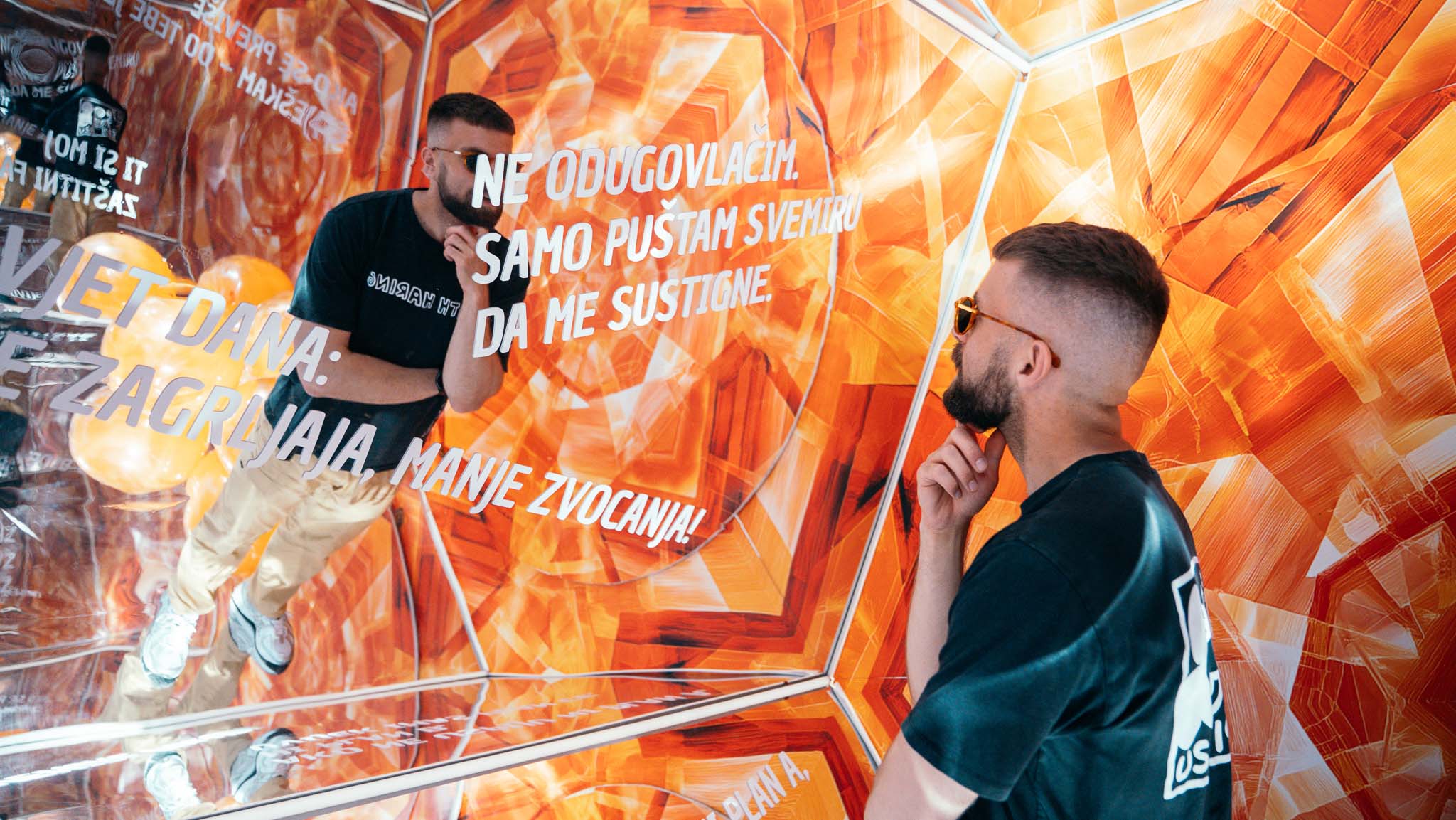 Cedevitaskop: posjetitelj pozira u narančastom zrcalnom kaleidoskopu, a odraz mu se ponavlja među porukama