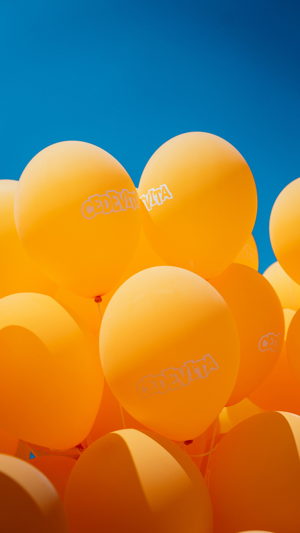 Grozd narančastih balona s Cedevita logom na vedrom plavom nebu