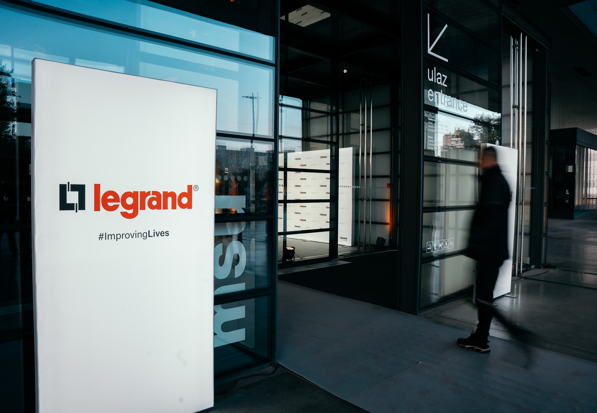 Legrand Light Now događanje: totem Legrand #ImprovingLives na ulazu u muzej dok gost ulazi unutra