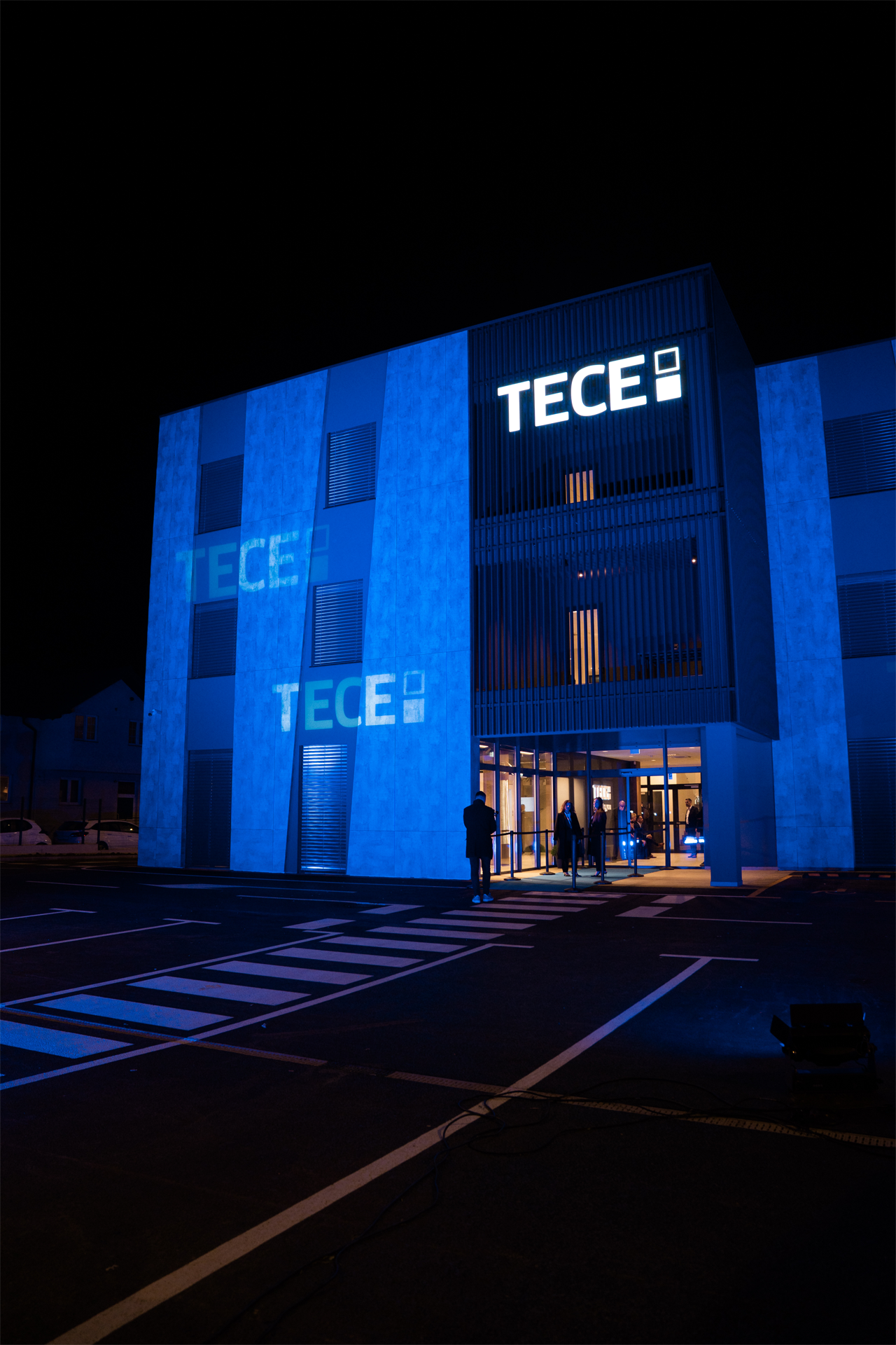 Nova zgrada TECE Adrie u Stupniku noću u plavom svjetlu, logotipi projicirani na fasadu dok gosti stižu