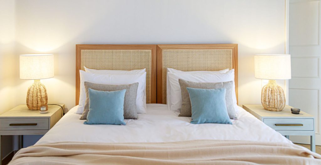 Guest bedroom fitted with rattan headboard, lightwood accents and modern sophisticated beach decor