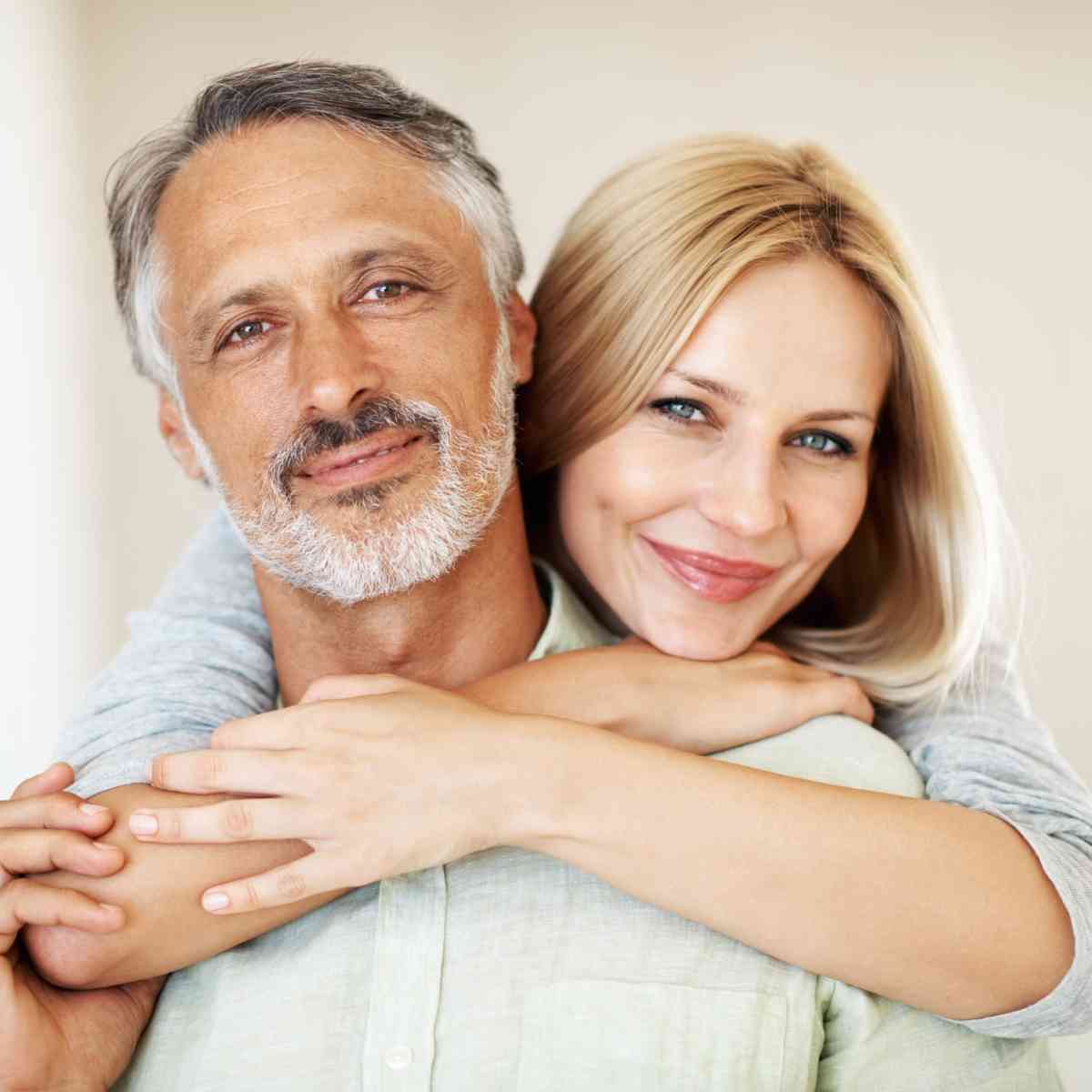 Älteres Paar, das sich umarmt und in die Kamera lächelt