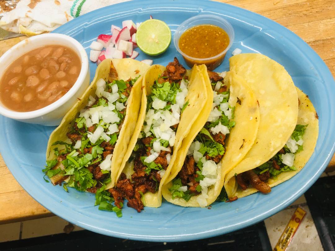 Beef tacos served with a side of beans and sauce.