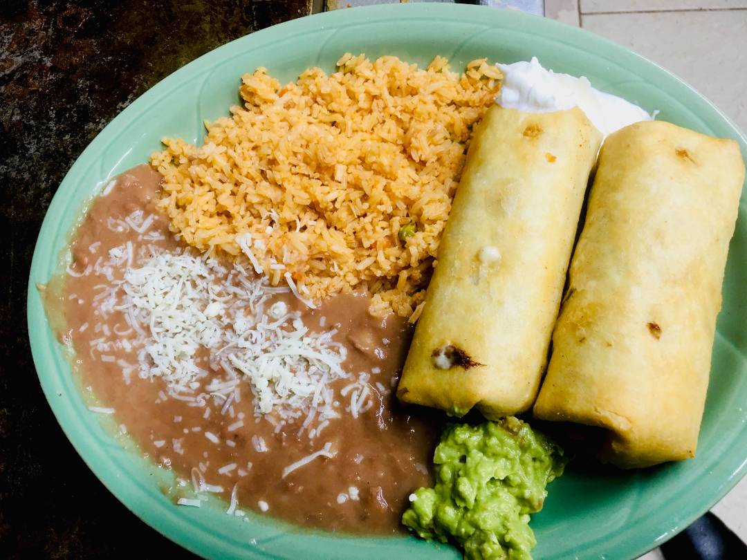 Plate of burritos served with rice, beans and a side of guacamole.