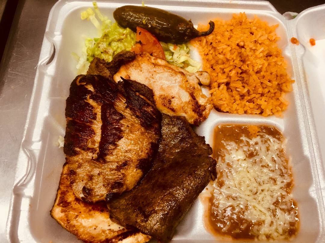 Steak with a mole sauce and a side of vegetables served with rice and beans.