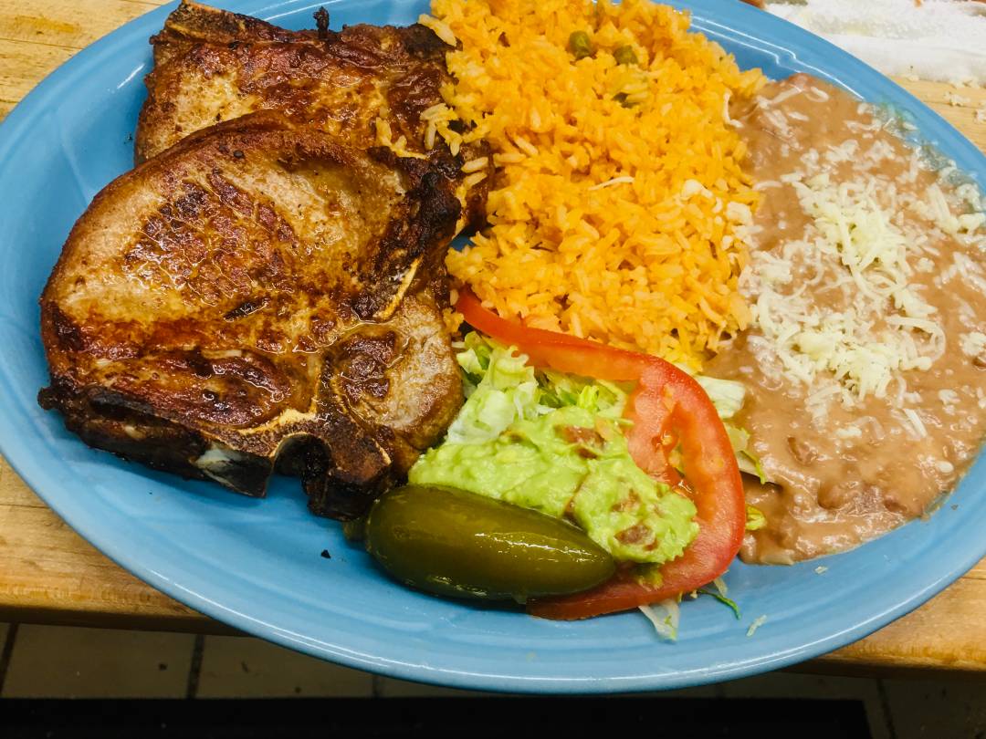 Steak on blue plate served with rice and beans, with a side of vegetables.