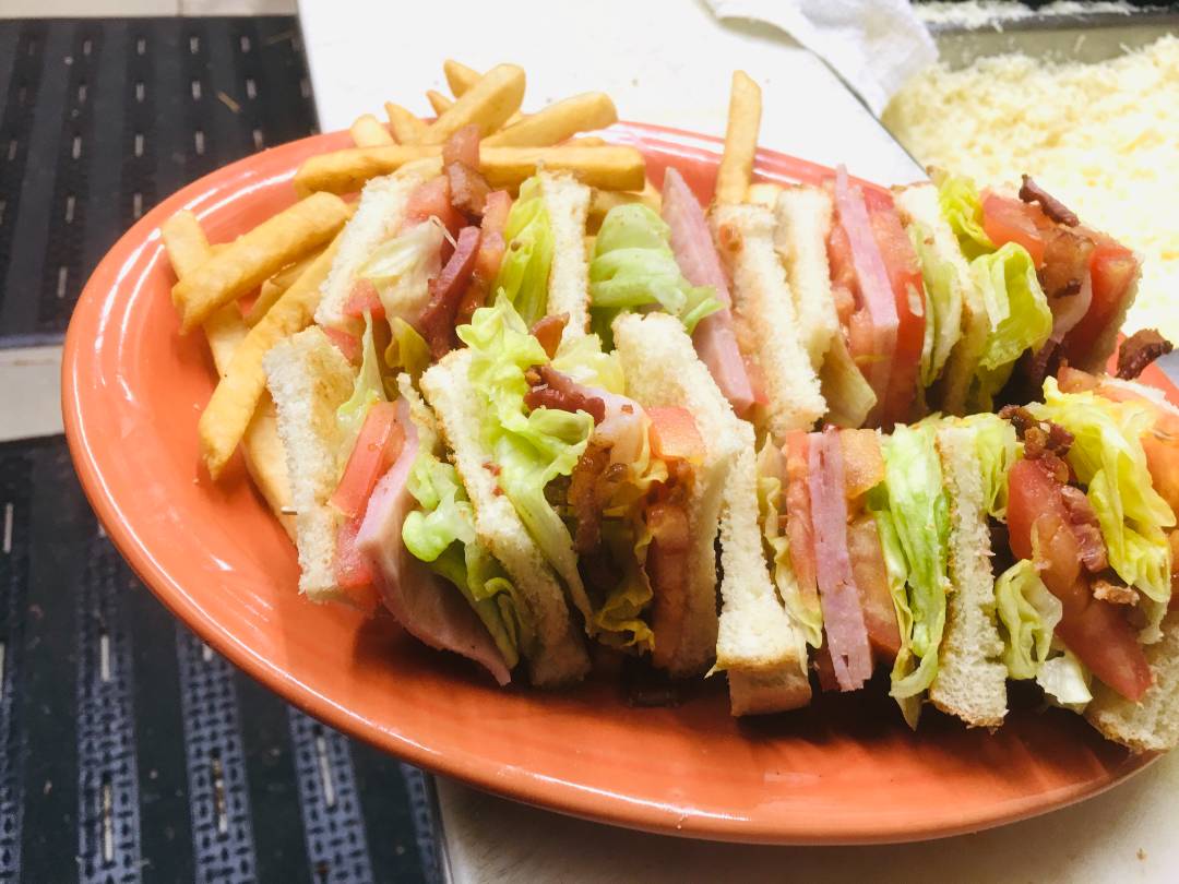 Meats and vegetables sandwich with fries.