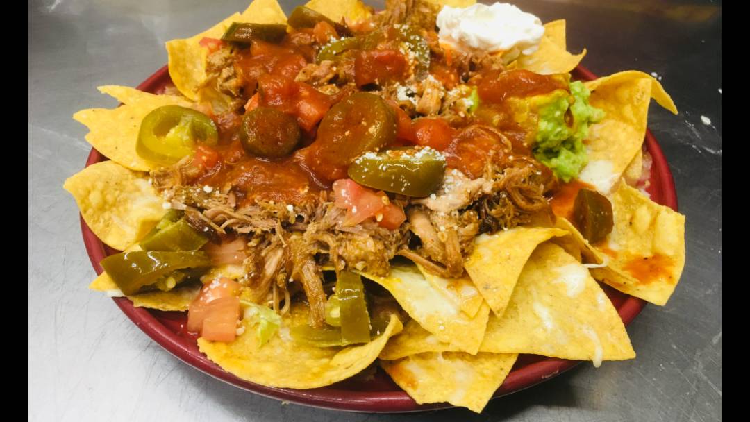 Nachos topped with meat, vegetables and cheese