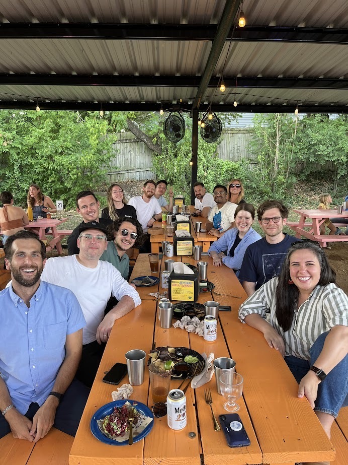 Group of coworkers enjoying lunch together at an outdoor picnic table