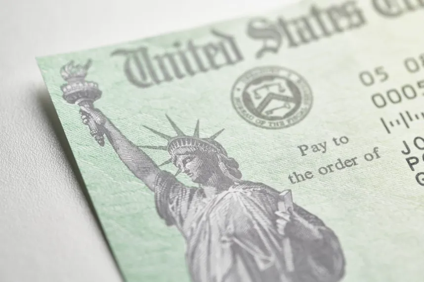 A close-up of a green U.S. Treasury check showing the Statue of Liberty icon and "United States" header, representing federal stimulus payments.