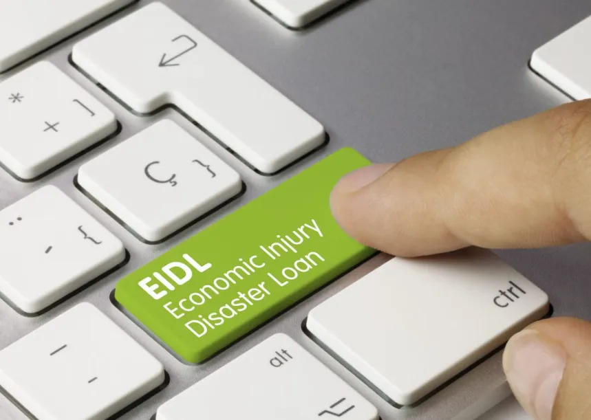 A close-up of a computer keyboard with a finger pressing a bright green key labeled "EIDL Economic Injury Disaster Loan."