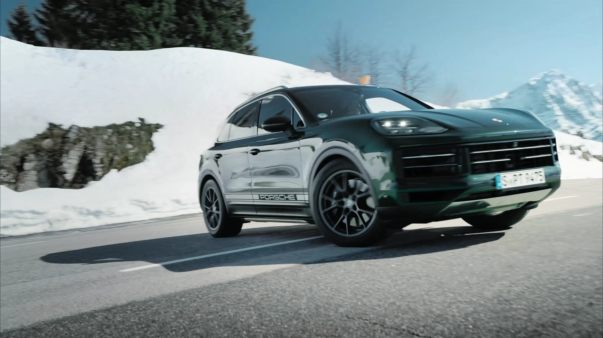 Porsche Cayenne Active in three quarter view on a snow lined mountain road, film still by IVORY Productions