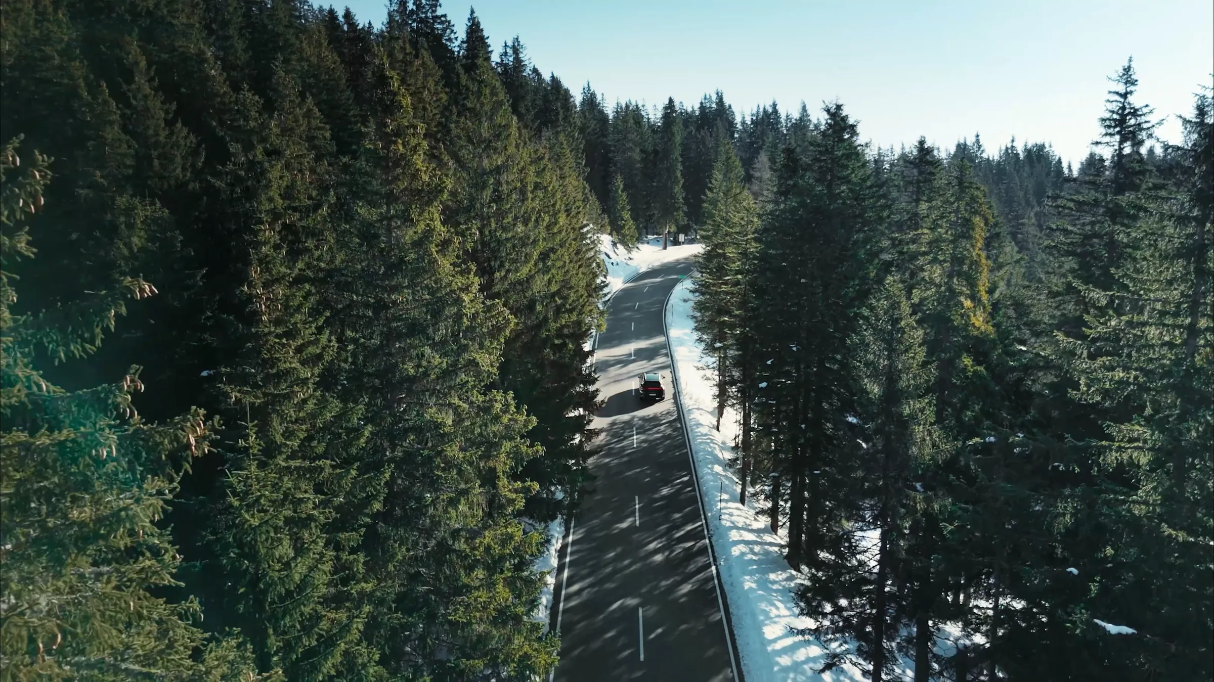 Aerial view of the Porsche Cayenne Active on a forest road through the Berchtesgaden Alps, film still by IVORY Productions