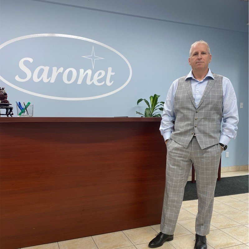 Man Standing in Front of Saronet Logo