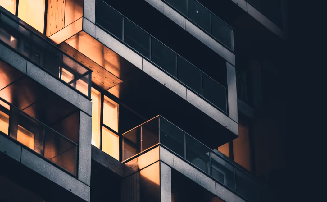 Façade d'un immeuble moderne avec balcons et fenêtres éclairées la nuit.