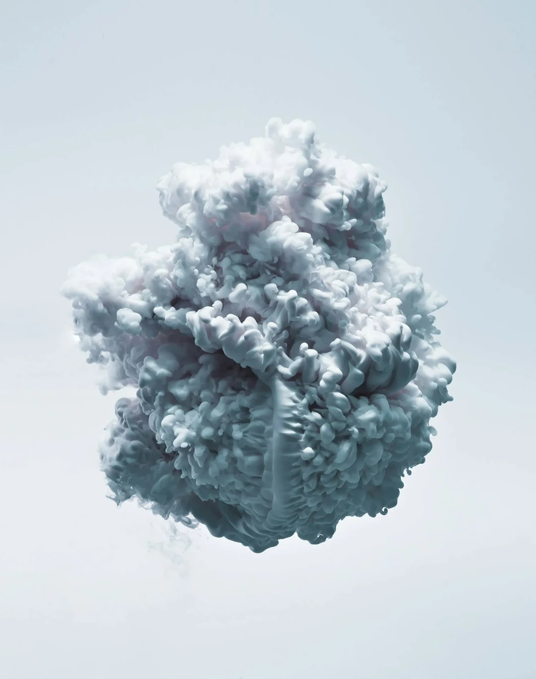 Nuage dense et tourbillonnant de fumée blanche sur fond clair.