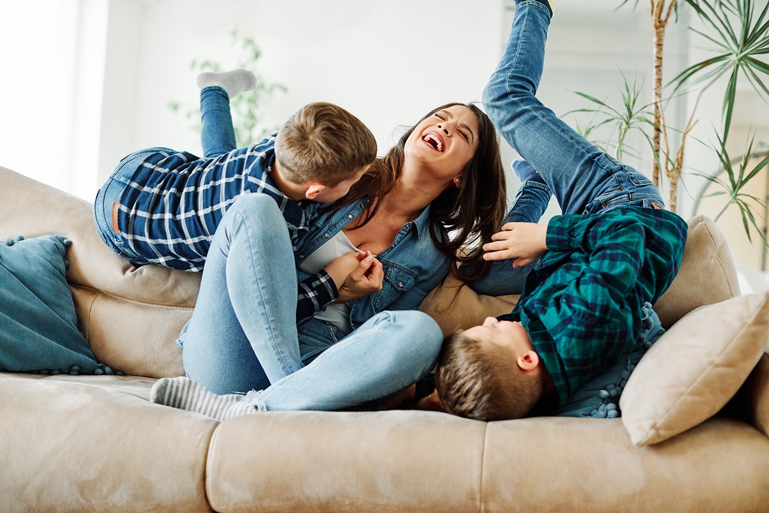 Mother and children playing happily on couch.