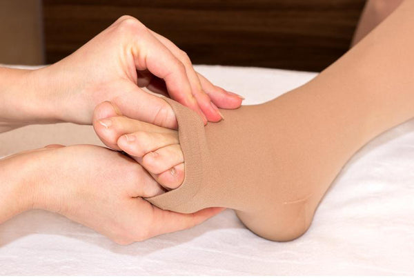 Woman fitting open toe compression stocking.