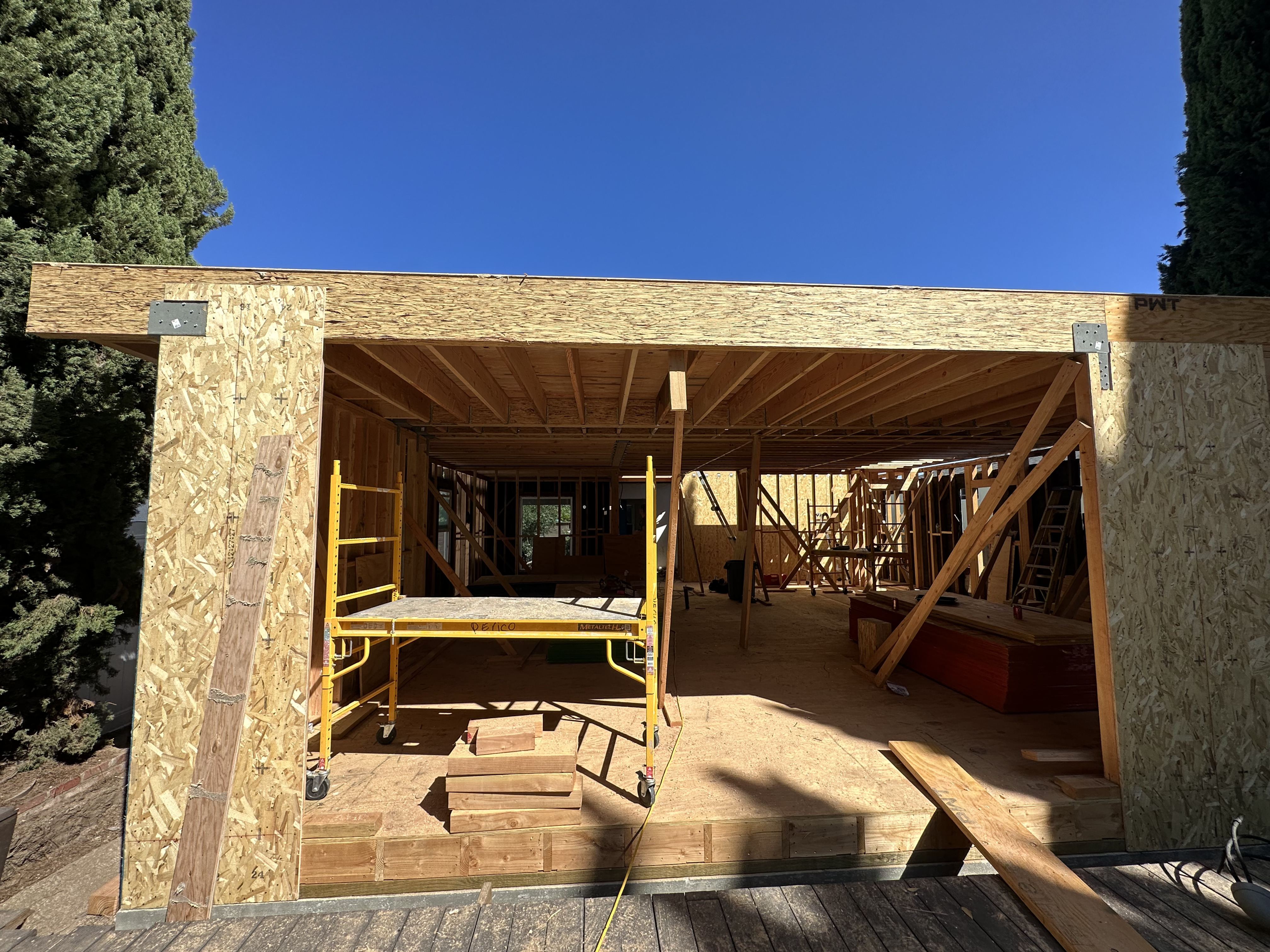 Wooden frame structure of a building under construction with construction materials and scaffolding inside.