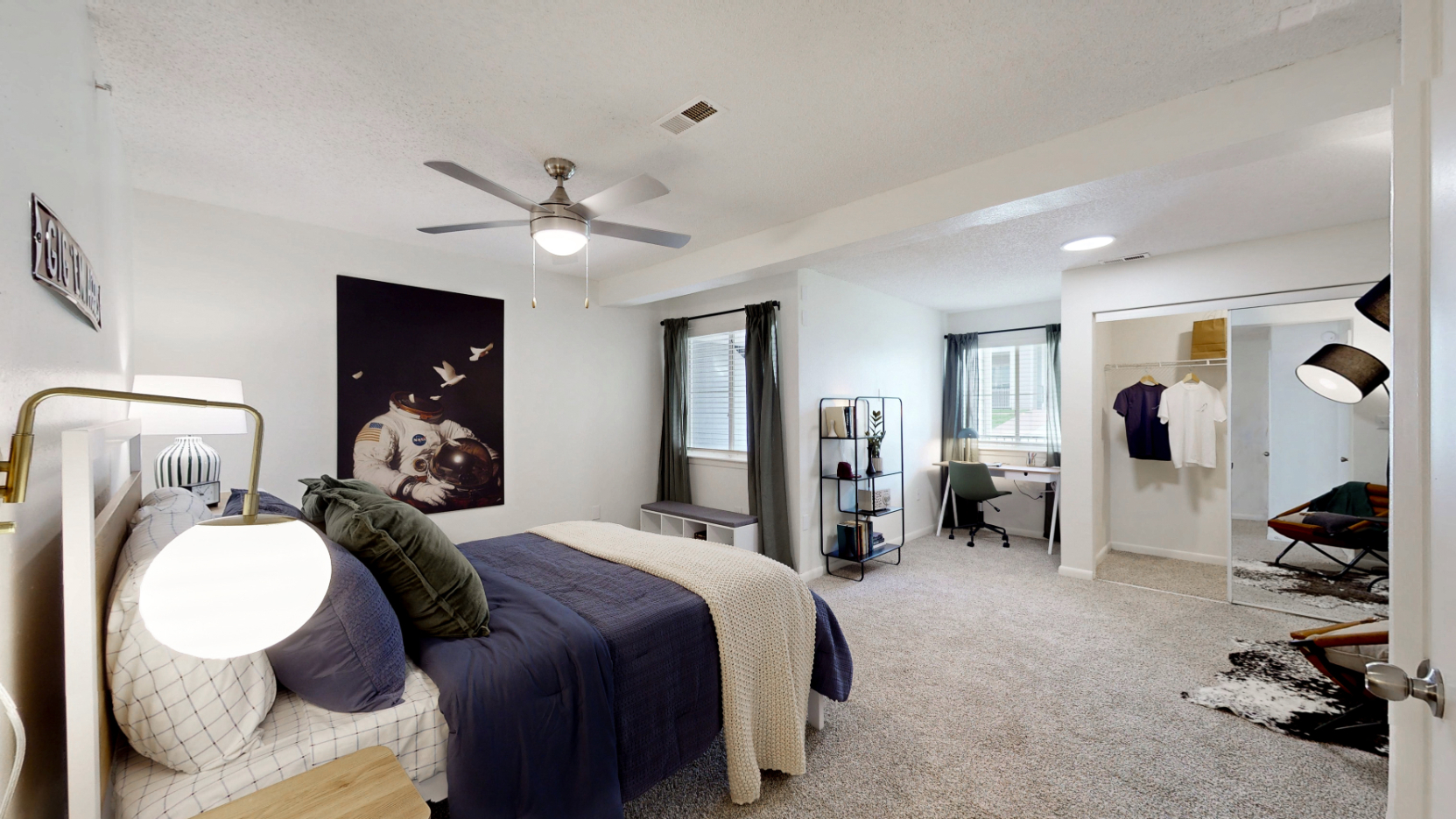 large bedroom with bed, closet with hangers, desk and window