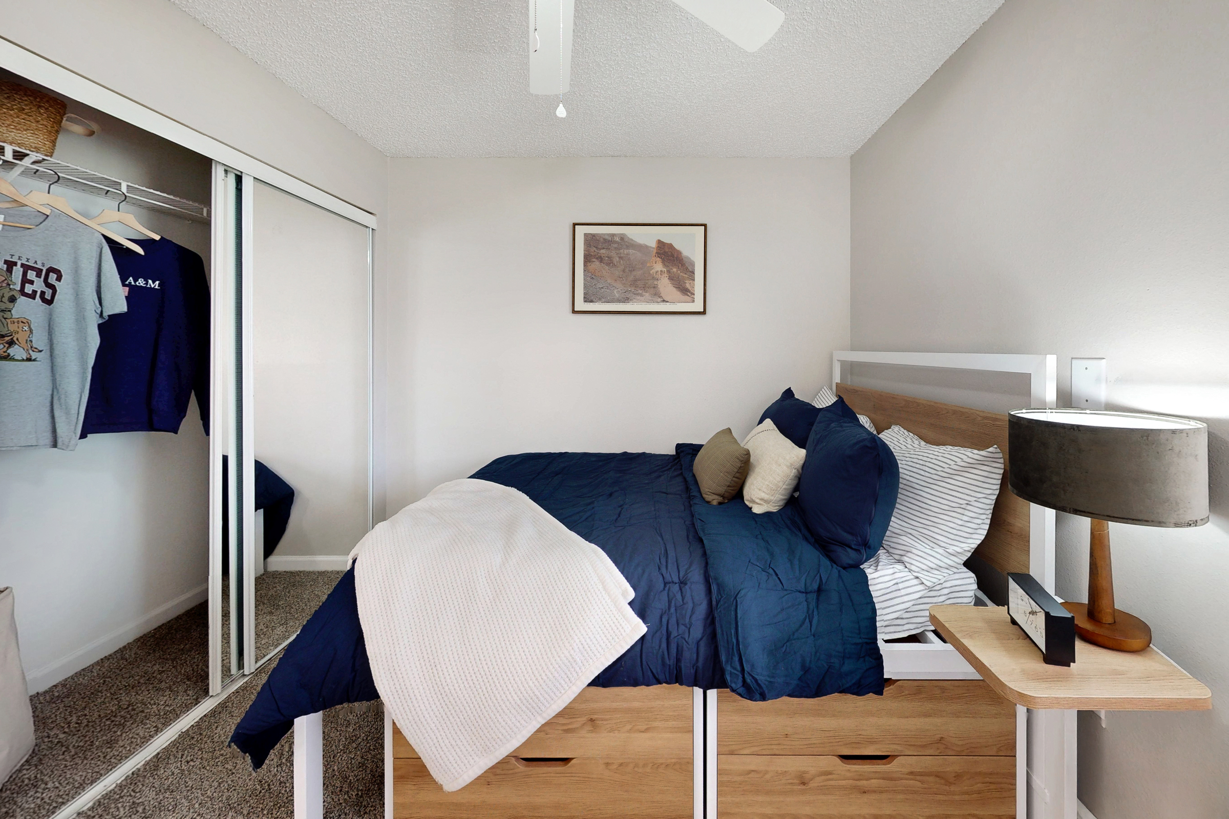 large bedroom with bed, closet with hangers, desk and window