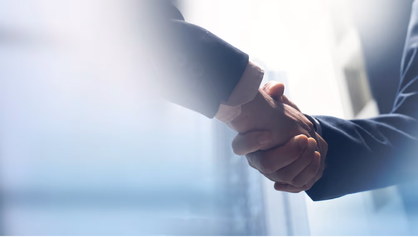 Two business professionals shaking hands, symbolizing a successful acquisition deal.