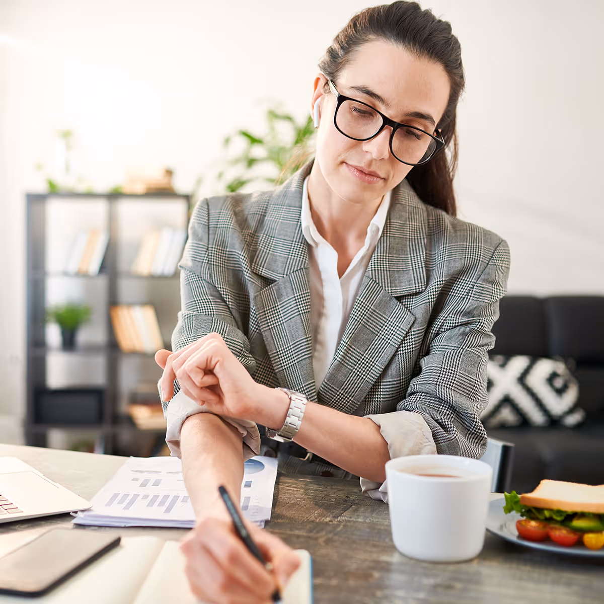 Tenet intern focused on notes and financial reports during a meeting.