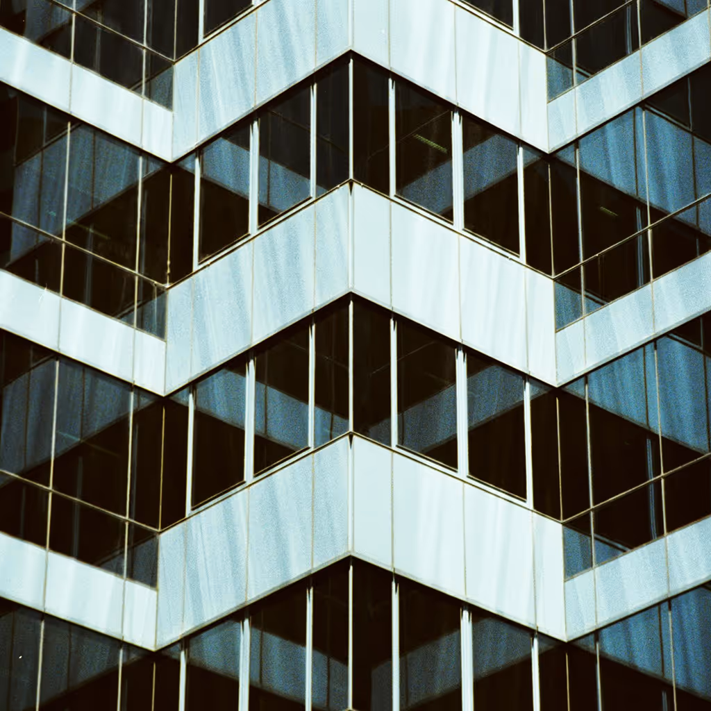 Close-up of a modern building corner with reflective glass windows and geometric patterns.